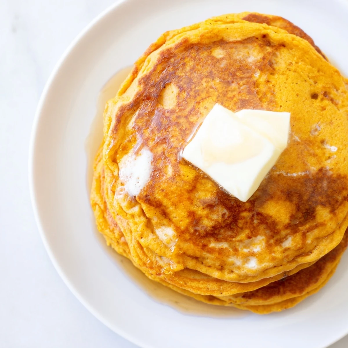 Golden, fluffy pumpkin spice pancakes piled high, ready to be drizzled with maple syrup.