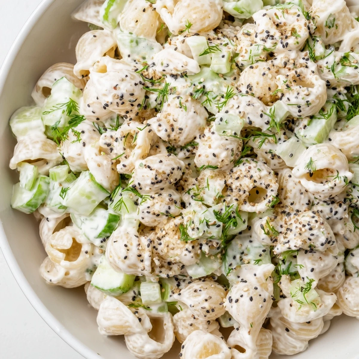Freshly cooked small shell pasta tossed with diced cucumbers, green onions, and dill in a creamy tangy dressing, topped with everything bagel seasoning.  