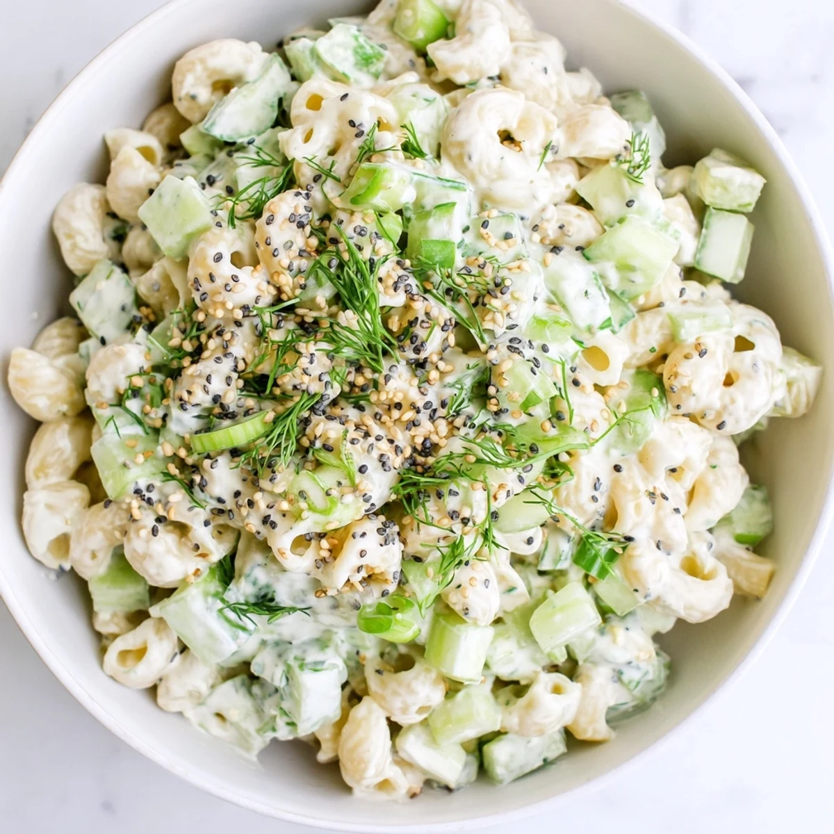 A vegetarian American side dish featuring tender pasta, crunchy cucumber pieces, and aromatic dill, lightly coated in a smooth sour cream-based dressing.