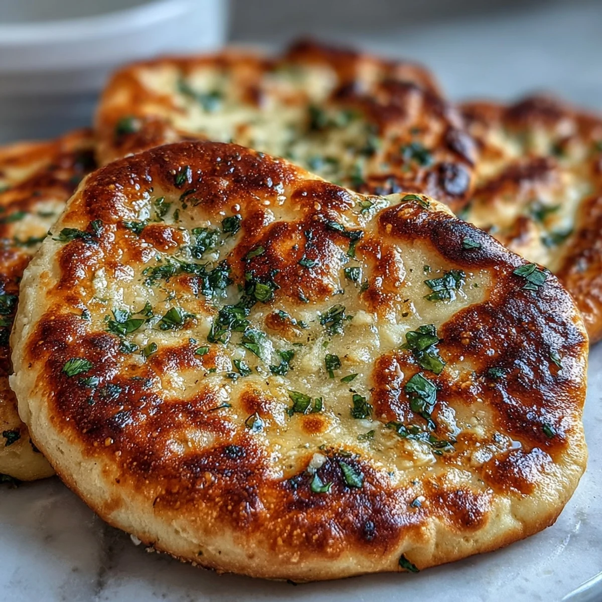 Freshly baked The Best Easy Garlic Naan Bread with golden bubbles and melted butter brushed on top.