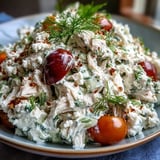 Spoonful of Tzatziki Chicken Salad topped with crumbled feta and Kalamata olives, served over vibrant spinach for a Mediterranean-inspired lunch.