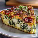 Fluffy spinach and feta frittata loaded with tangy sun-dried tomatoes and savory herbs, baked to golden perfection for a satisfying brunch.