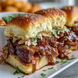 Smoky BBQ brisket piled high on soft slider buns, topped with tangy slaw for a flavorful bite at your party.