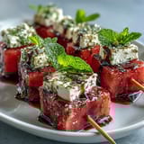Colorful watermelon feta mint skewers drizzled with olive oil, perfect for light party snacks.  