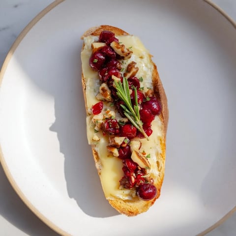 Golden, toasted Festive Holiday Cranberry and Brie Crostini, topped with bubbly cranberry sauce and creamy brie.