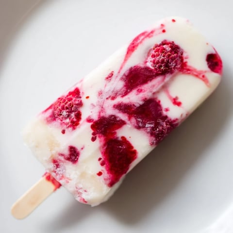 Vibrant Raspberry Coconut Ice Pops: A cross-section revealing layers of red fruit and creamy white coconut.