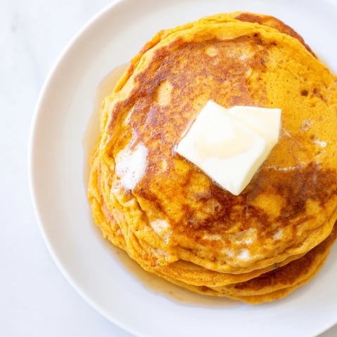 Golden, fluffy pumpkin spice pancakes piled high, ready to be drizzled with maple syrup.