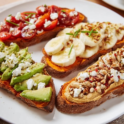 Golden roasted sweet potato slices topped with sliced avocado and cherry tomatoes for a savory breakfast snack.  