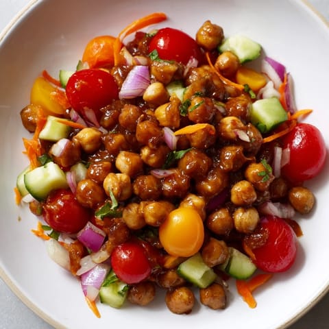 A colorful bowl of BBQ Chickpea Salad, featuring zesty sauce over beans and peppers.