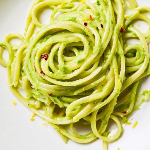 Twirling spaghetti coated in vibrant avocado sauce, a zesty, satisfying vegetarian main dish.