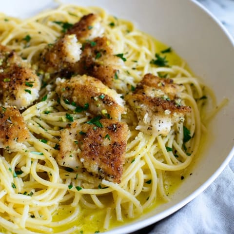 A close-up of Crispy Fish Pasta featuring pan-fried white fish and bright parsley on a rustic plate.  