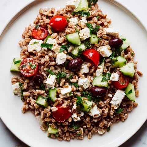 Tossed Farro Salad Mediterranean with zesty lemon-oregano dressing and fresh herbs in a rustic bowl.