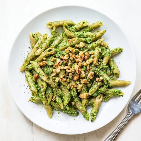 A spoonful of luscious, plant-based creamy spinach walnut pasta, featuring a smooth walnut and spinach blend, ready to serve.  