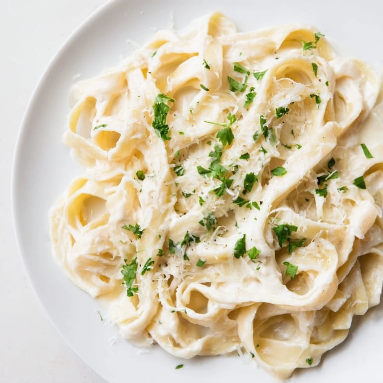 A close-up of pasta coated in flavorful sauce. This Pasta Alfredo Cottage Hack looks delicious and comforting.