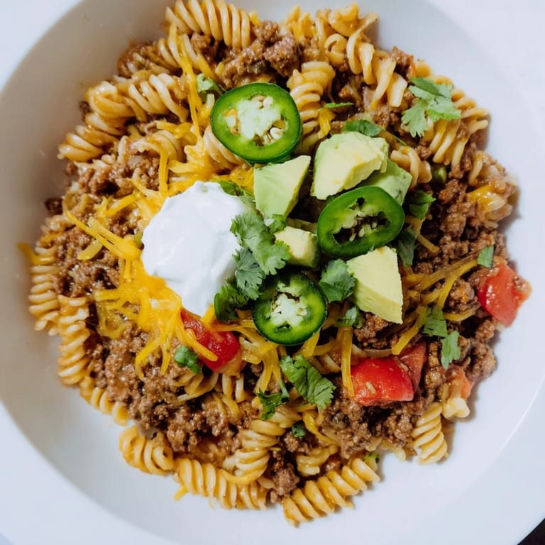A close-up of a bubbling Beef Taco Pasta Skillet, with cheese melted over the savory dish.