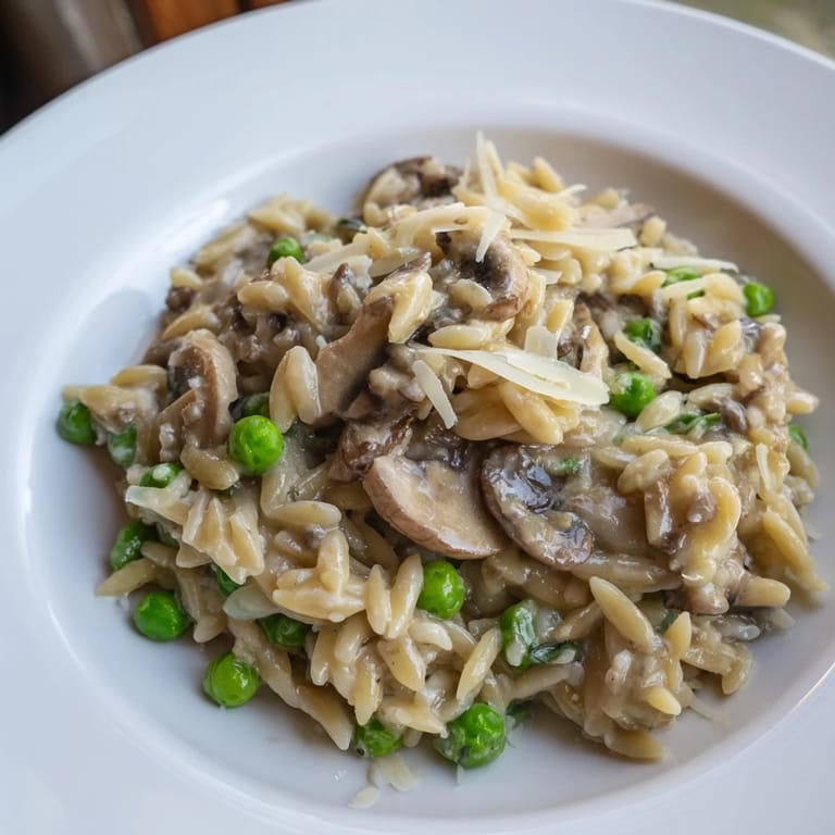 Golden orzo mushroom risotto-style pasta with earthy mushrooms and Parmesan, garnished with parsley on a rustic plate.